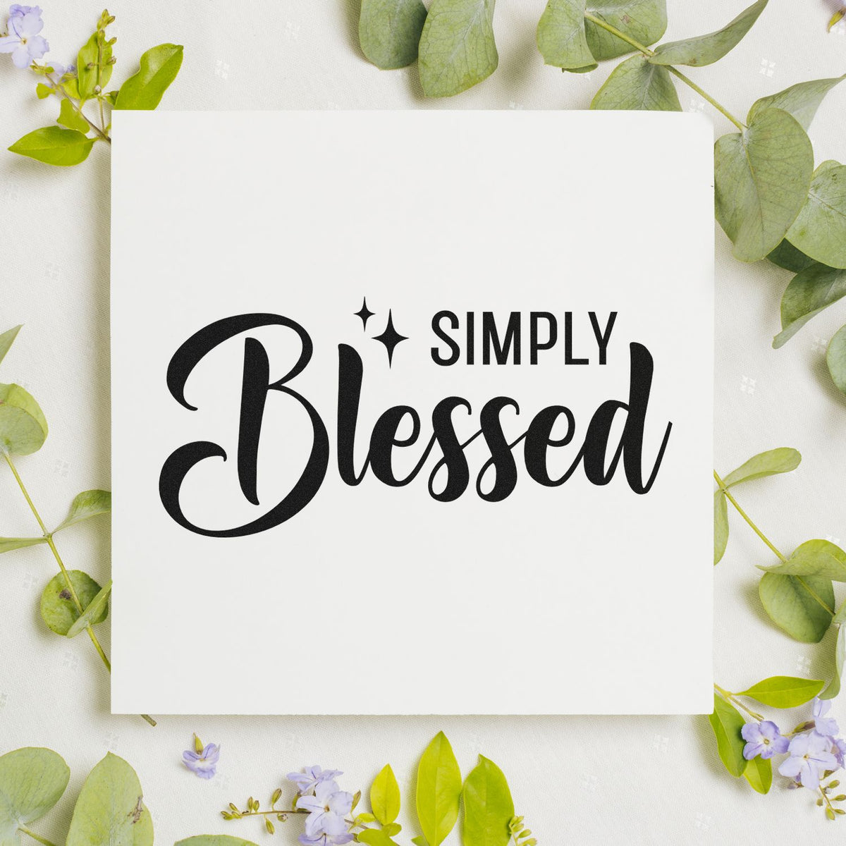 White custom stamp and seal with black Simply Blessed lettering, framed by green leaves and lavender flowers.
