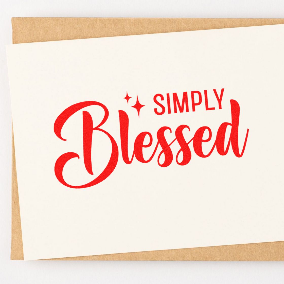 Red Simply Blessed stamp on a white card over a tan envelope, with sparkles, for stamp and seal products.