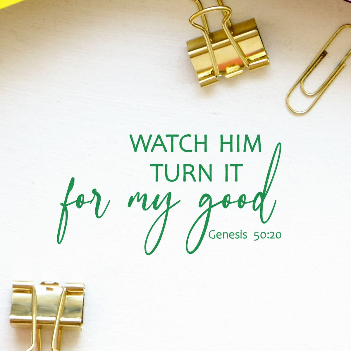 Green Genesis 50:20 scripture stamp and seal on white paper, accented by gold binder clips and paperclip.