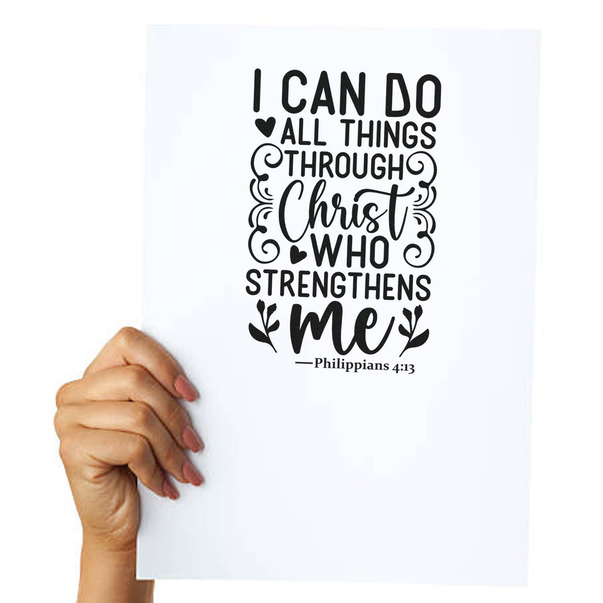 Hand holding white paper with black stamp-and-seal design reading I can do all things through Christ who strengthens me, with hearts and flourishes.