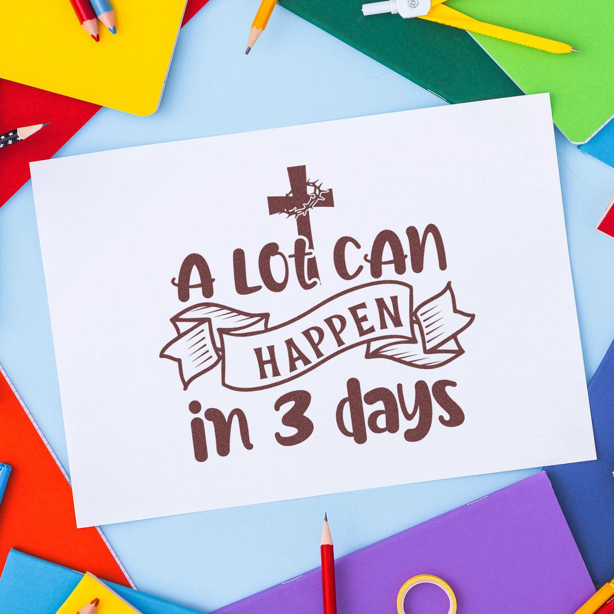 White card with brown stamp-and-seal text A Lot Can Happen in 3 days, on a colorful background of notebooks and pencils.