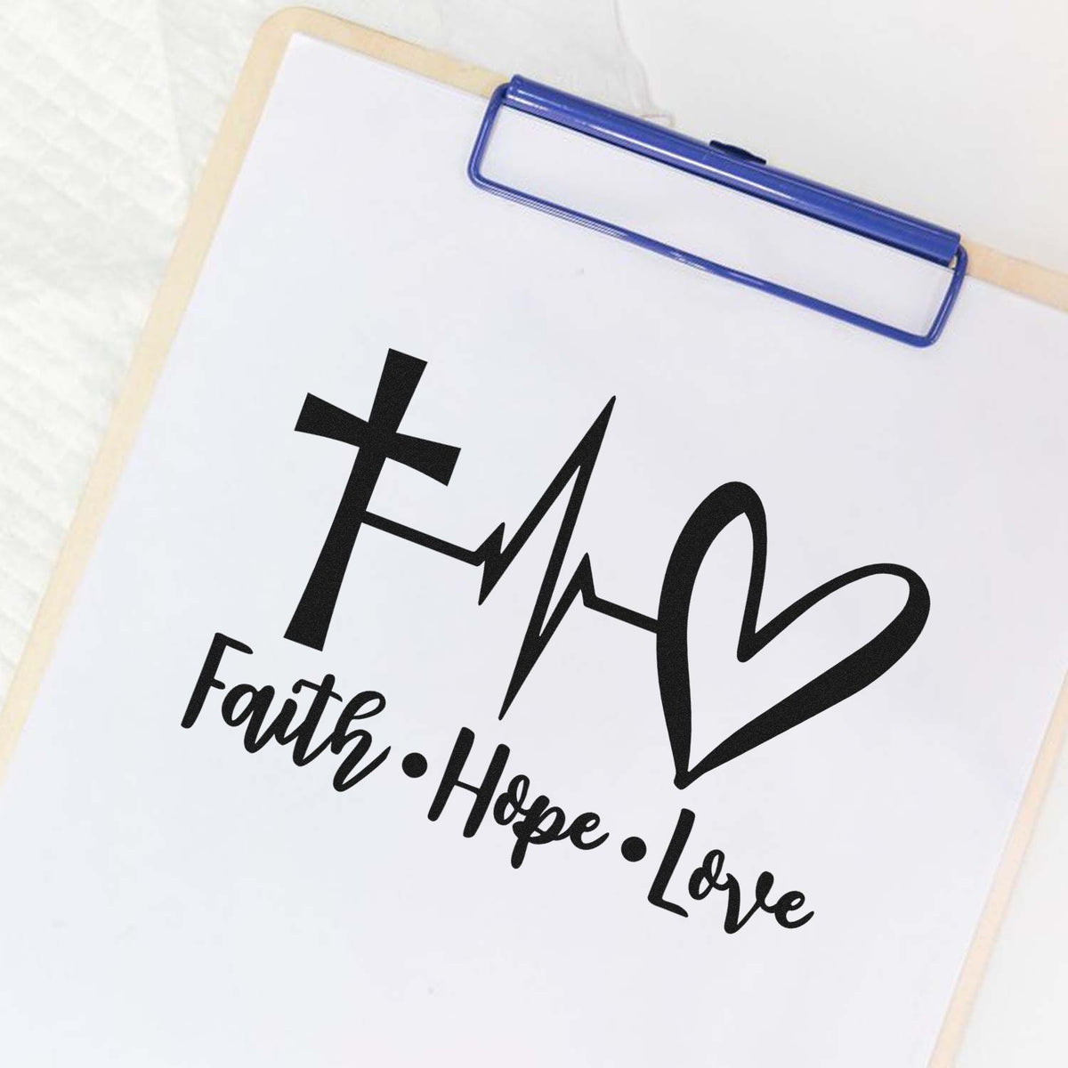 Blue clipboard displaying a black faith, hope, love stamp and seal design with cross, heartbeat line and heart.