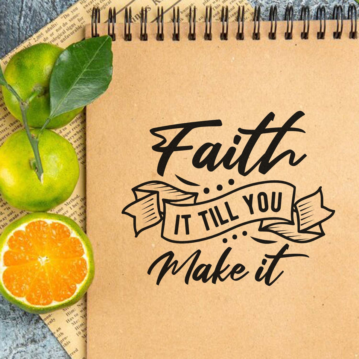 Black faith quote stamp/seal on kraft notebook with green limes and orange slice