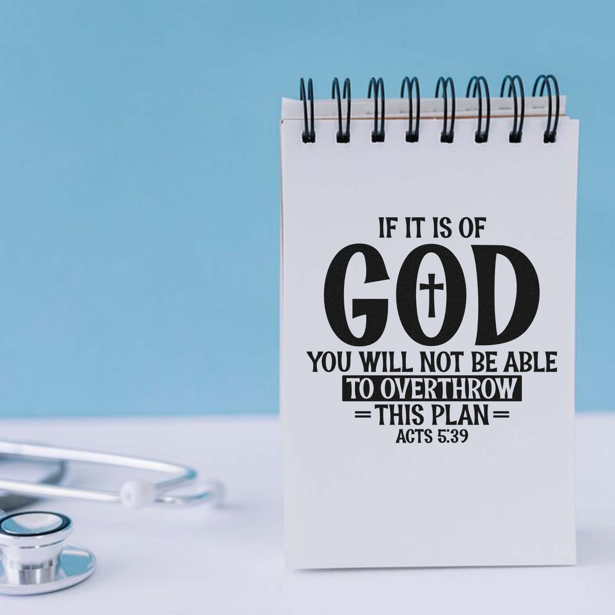 Custom stamp and seal notepad with black scripture text on a white page, set against a light blue background and stethoscope.