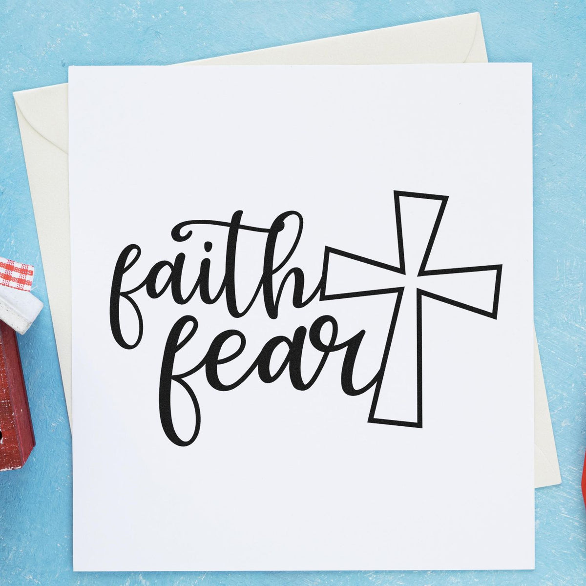 Black faith over fear cross design on white card, with blue background, envelopes, and stamp and seal products.
