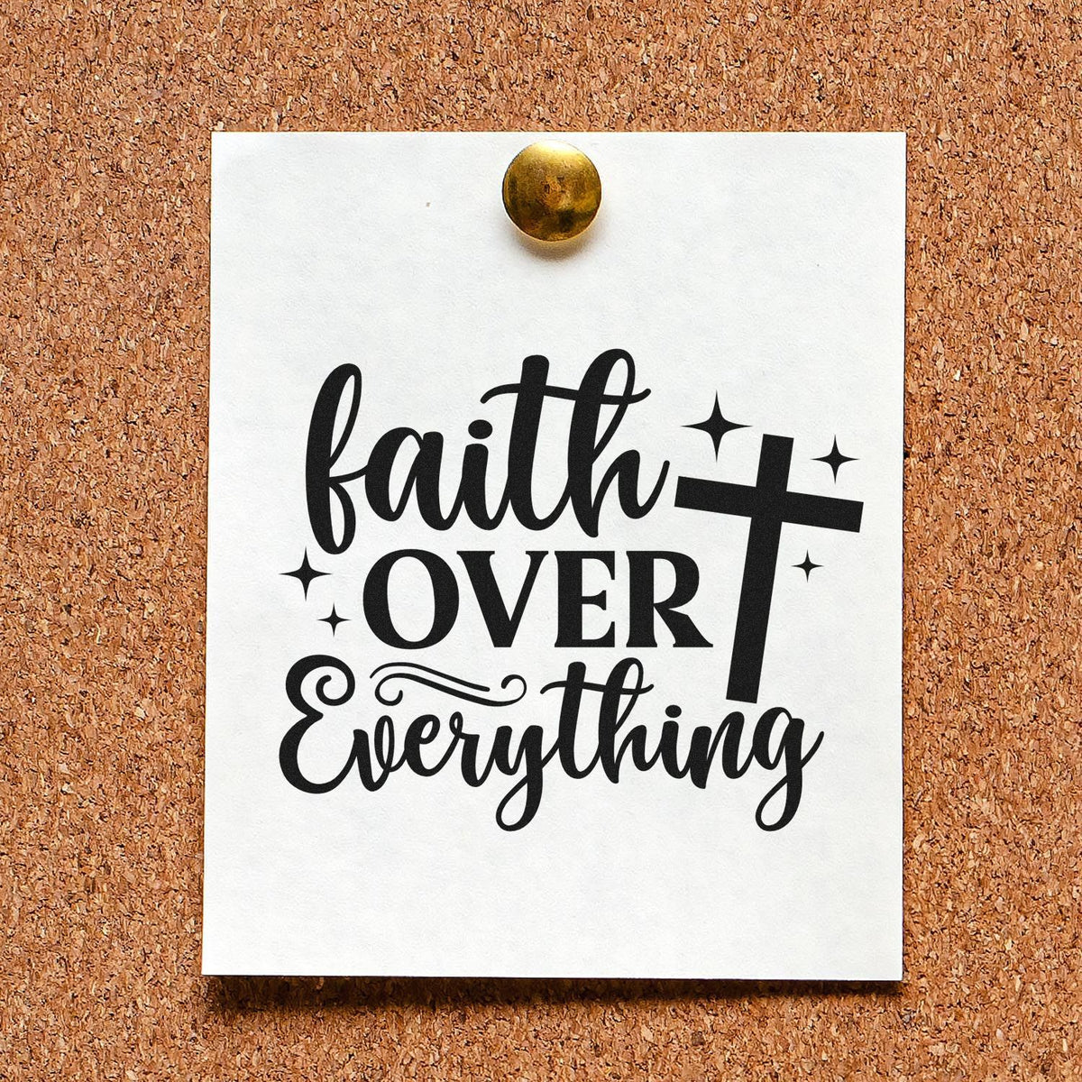 Black Faith Over Everything stamp/seal design with cross and sparkles on a white card pinned to corkboard.