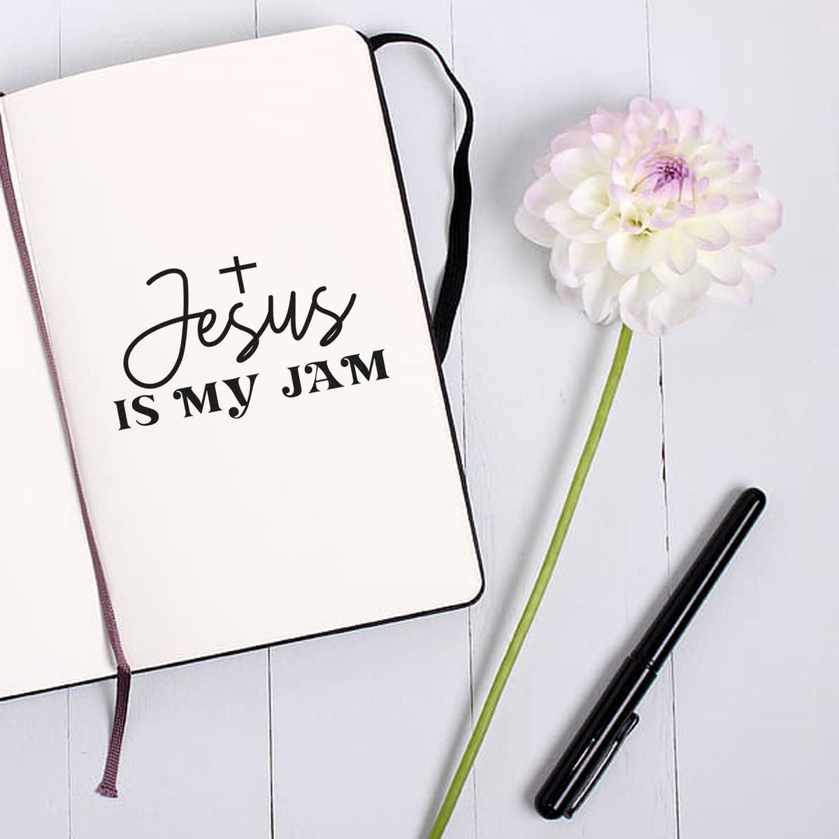 Custom stamp and seal products: cream notebook with black Jesus is my jam text, white flower, and black pen.