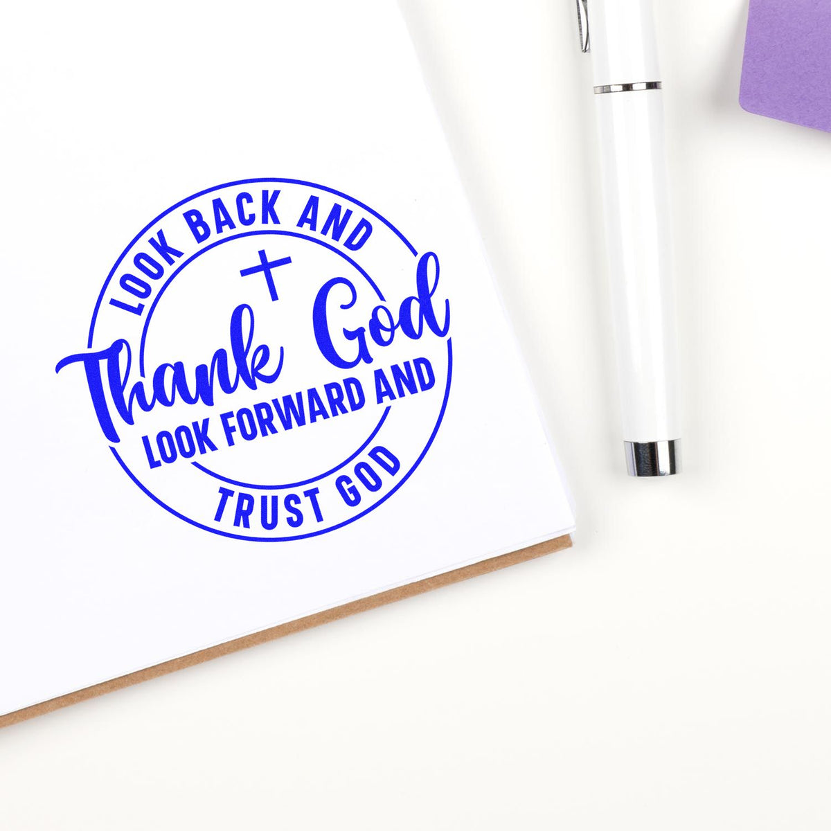 Blue circular thank-you stamp seal with Look Back and Thank God, Look Forward and Trust God beside a white pen.