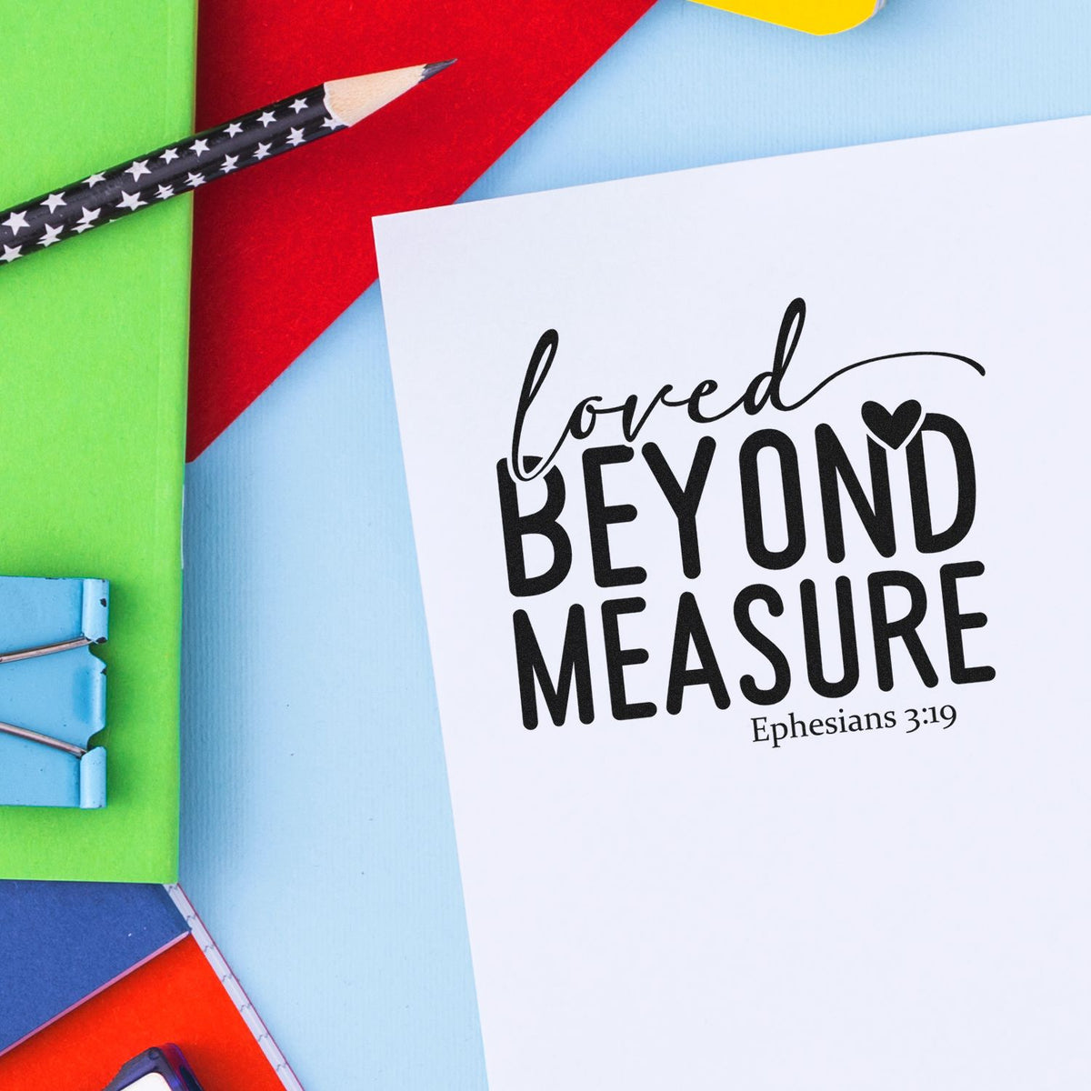 White stamp and seal sample reading Loved Beyond Measure Ephesians 3:19, on bright green, red, blue, and yellow paper.