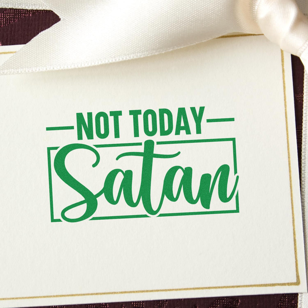 White gift tag with green Not Today Satan stamp seal, gold border, and satin ribbon.