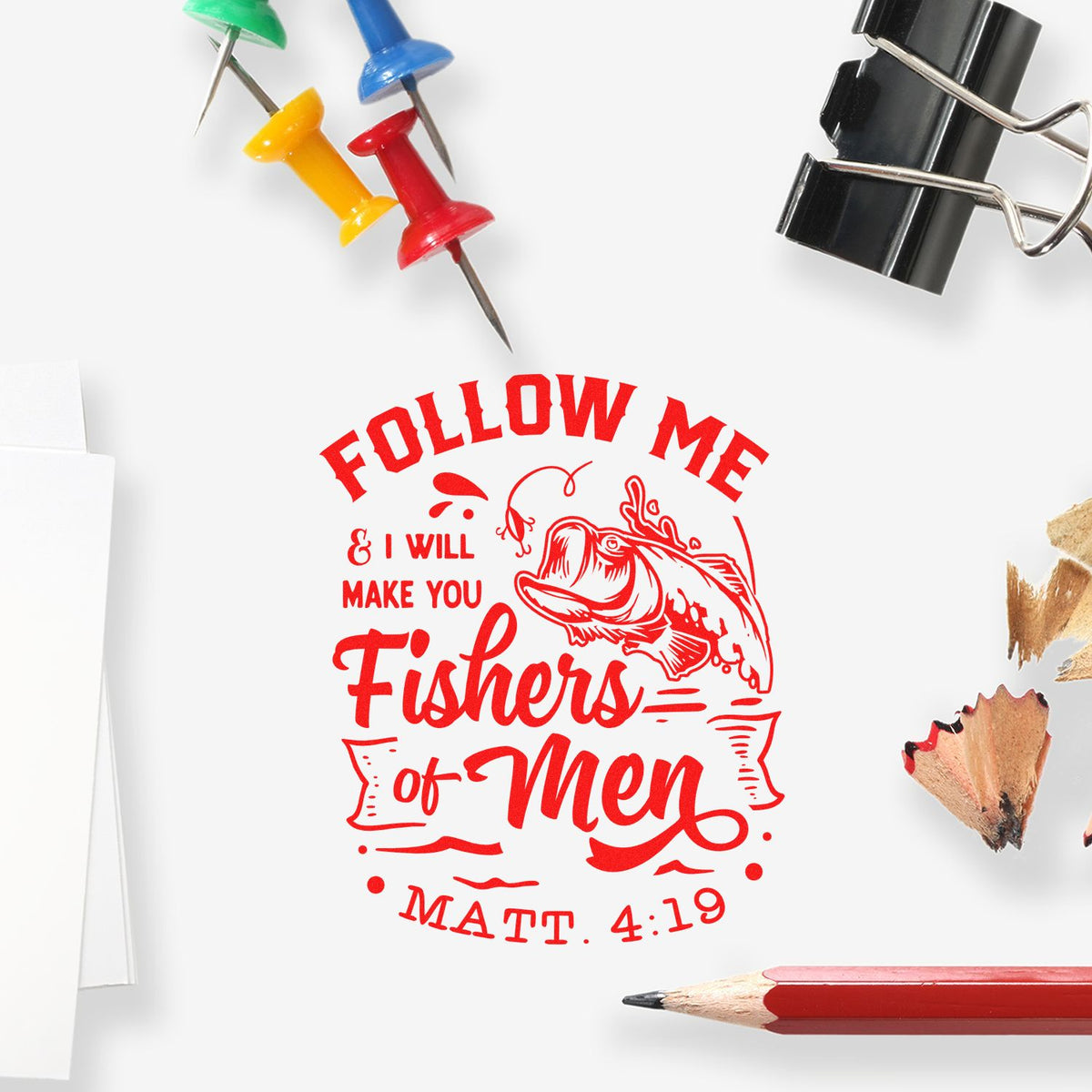 Red stamp seal with Follow Me & I Will Make You Fishers of Men text, fish graphic, colorful push pins, clip, and pencil