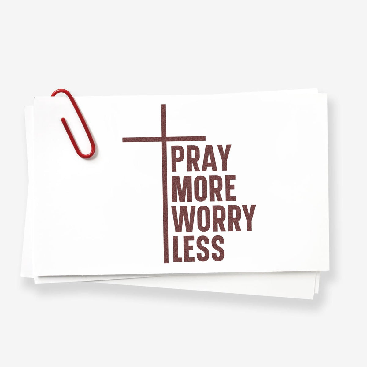 White stamp and seal cards with red paperclip, featuring a brown cross and PRAY MORE WORRY LESS text.