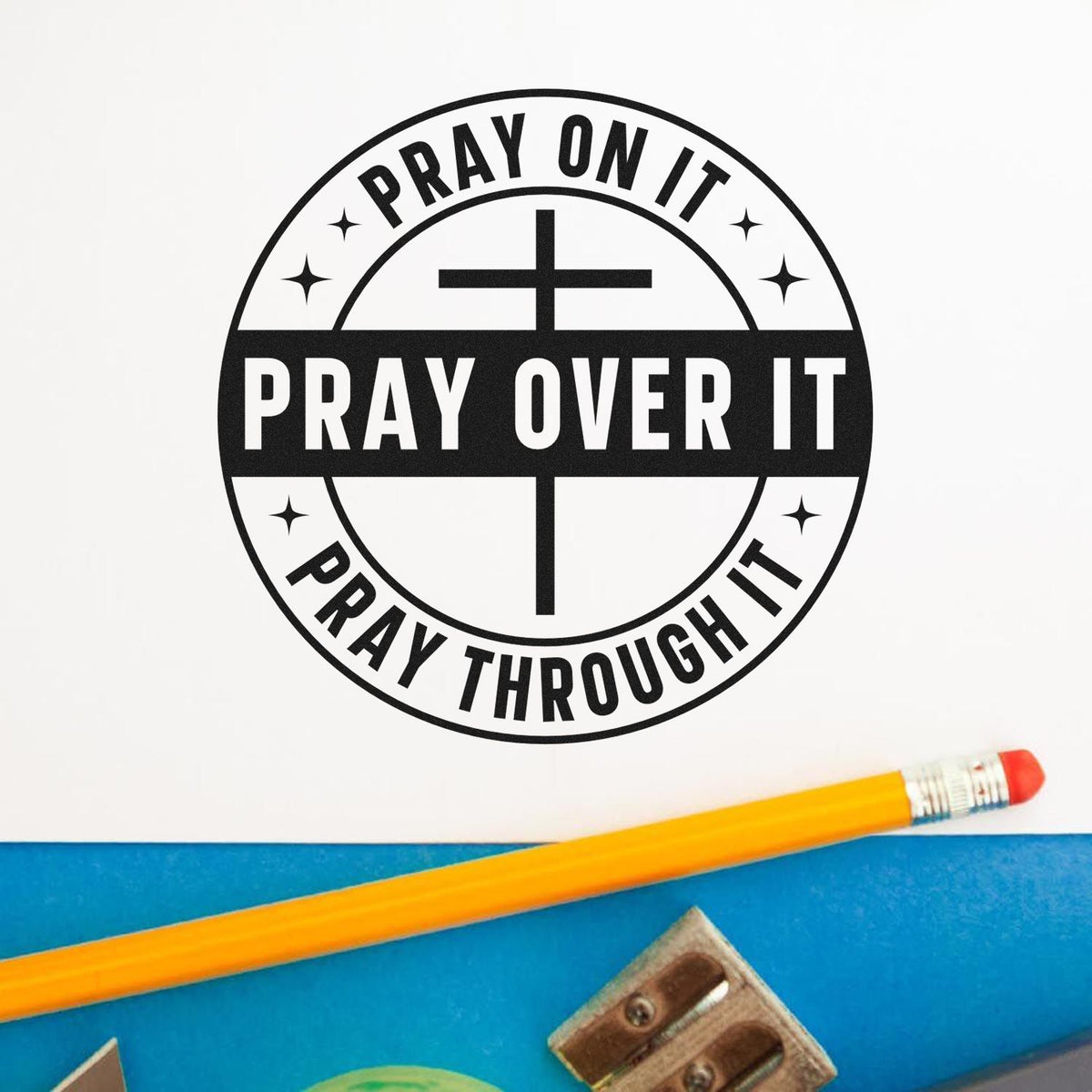 Black circular prayer stamp seal with cross and Pray on it, Pray over it, Pray through it in black on white, with yellow pencil.