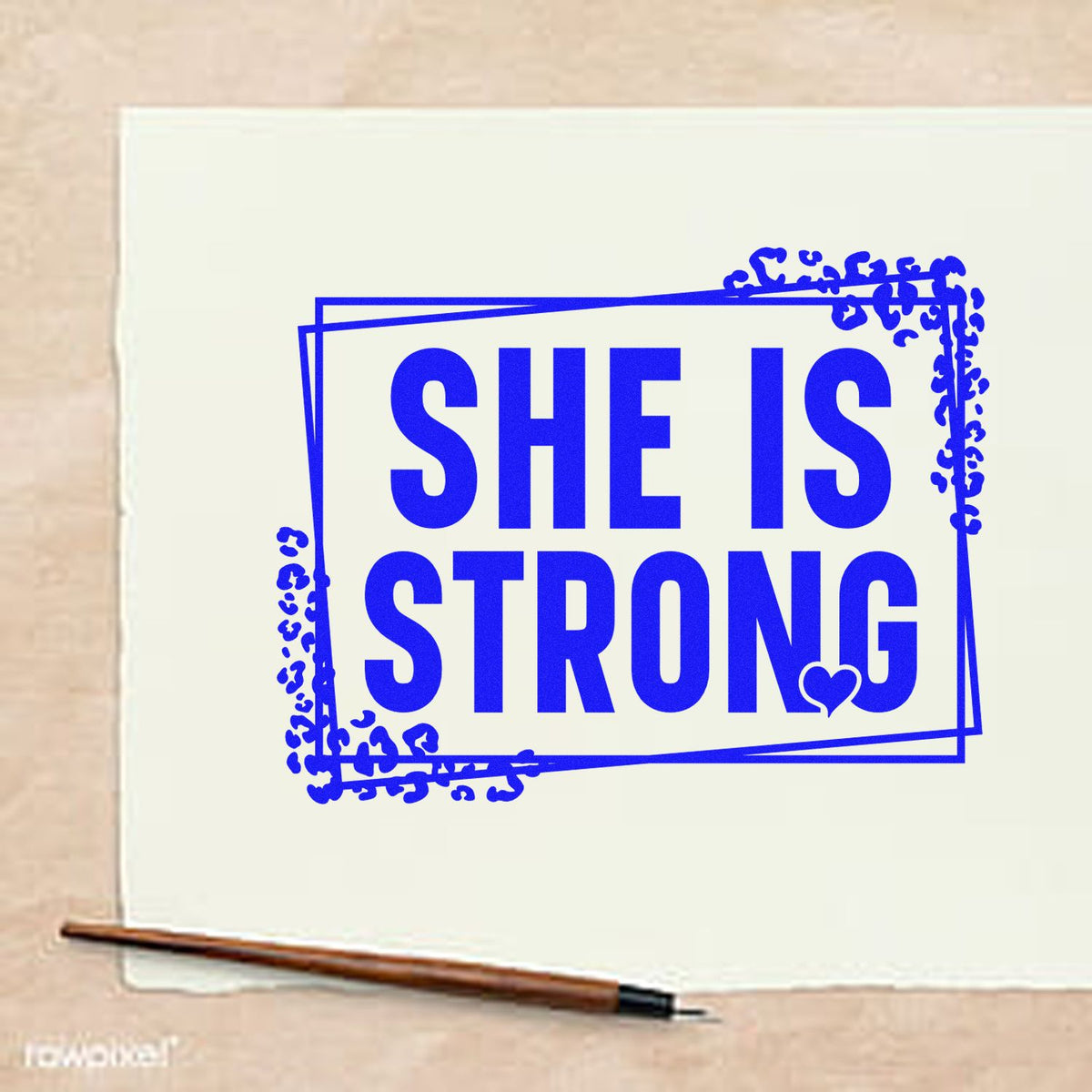 Blue rubber stamp seal reading SHE IS STRONG with decorative border and heart on cream paper.