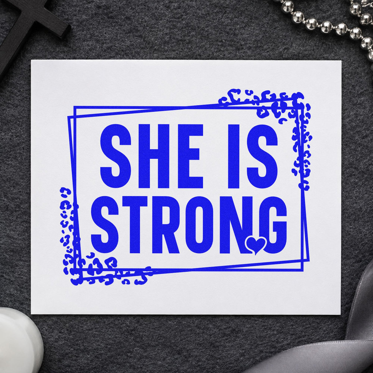 She Is Strong craft stamp imprinted in blue ink on paper, a design suited to widow support notes.
