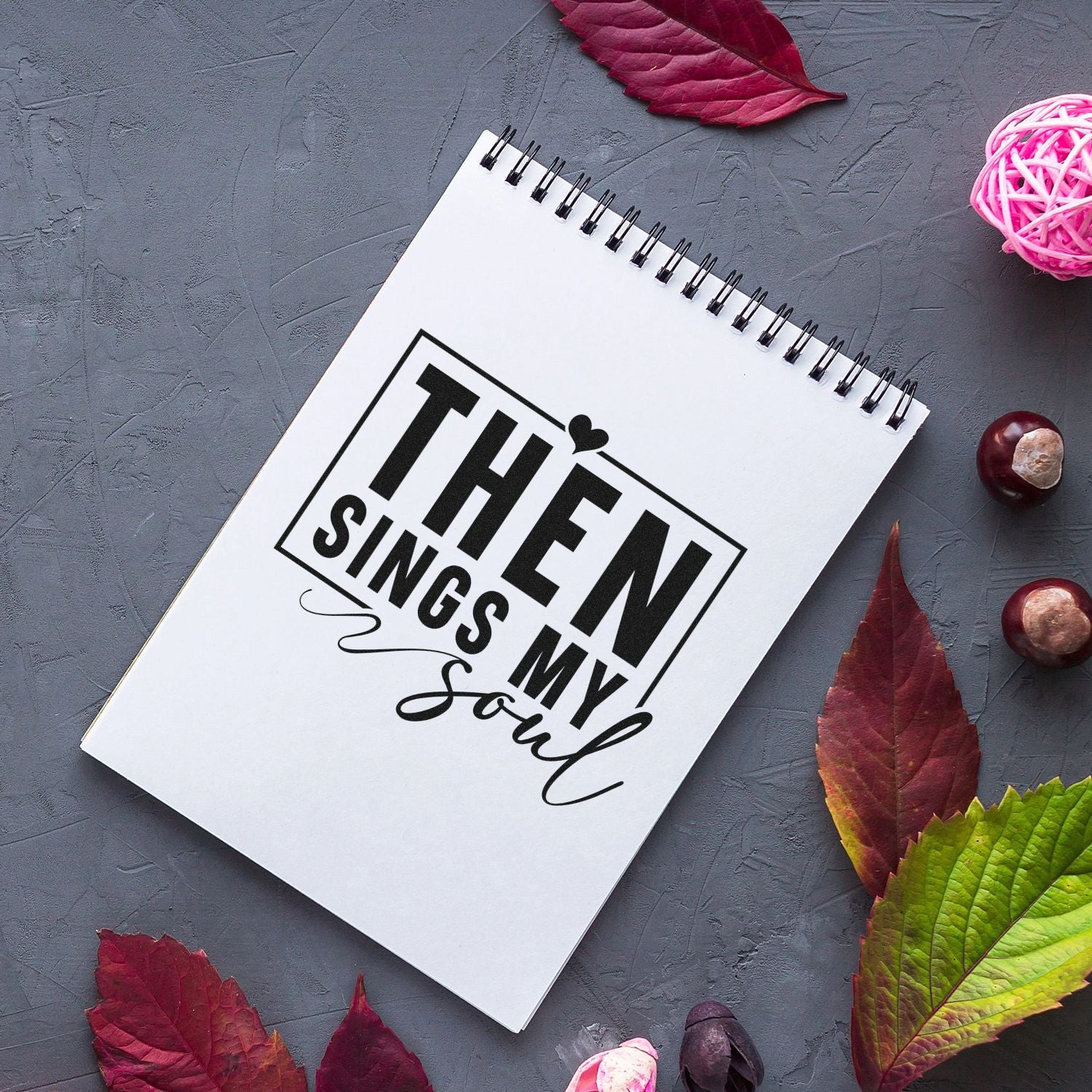 Custom stamp and seal design on white spiral notebook with black Then Sings My Soul lettering, on a gray background with red leaves.