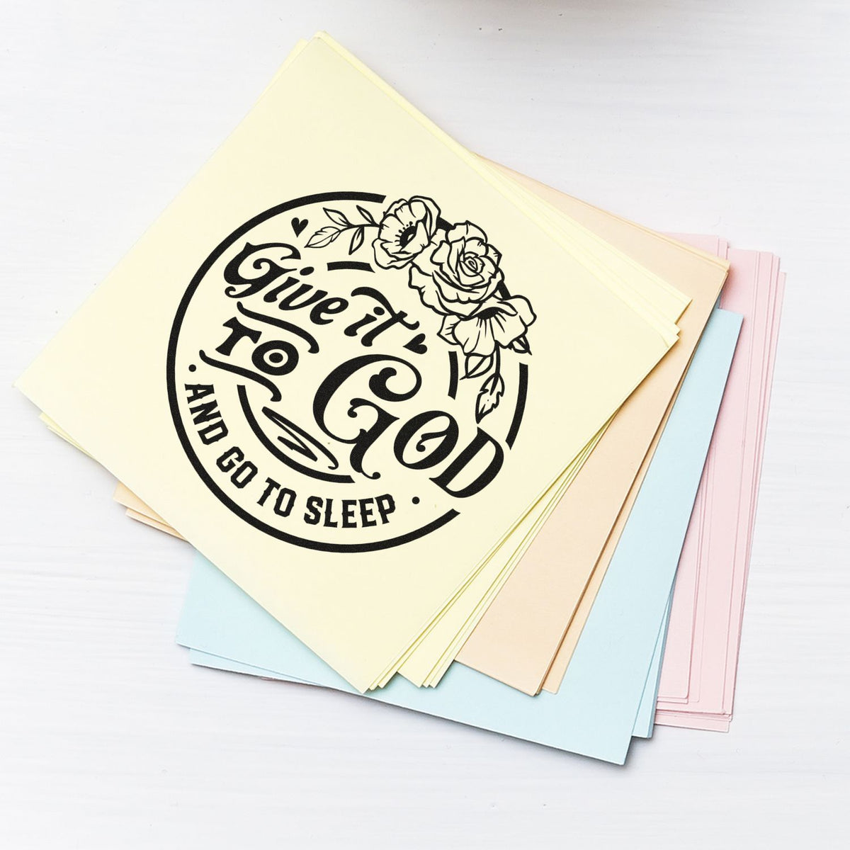 Cream, blue and pink cardstock stack with black floral stamp seal reading Give it to God and go to sleep