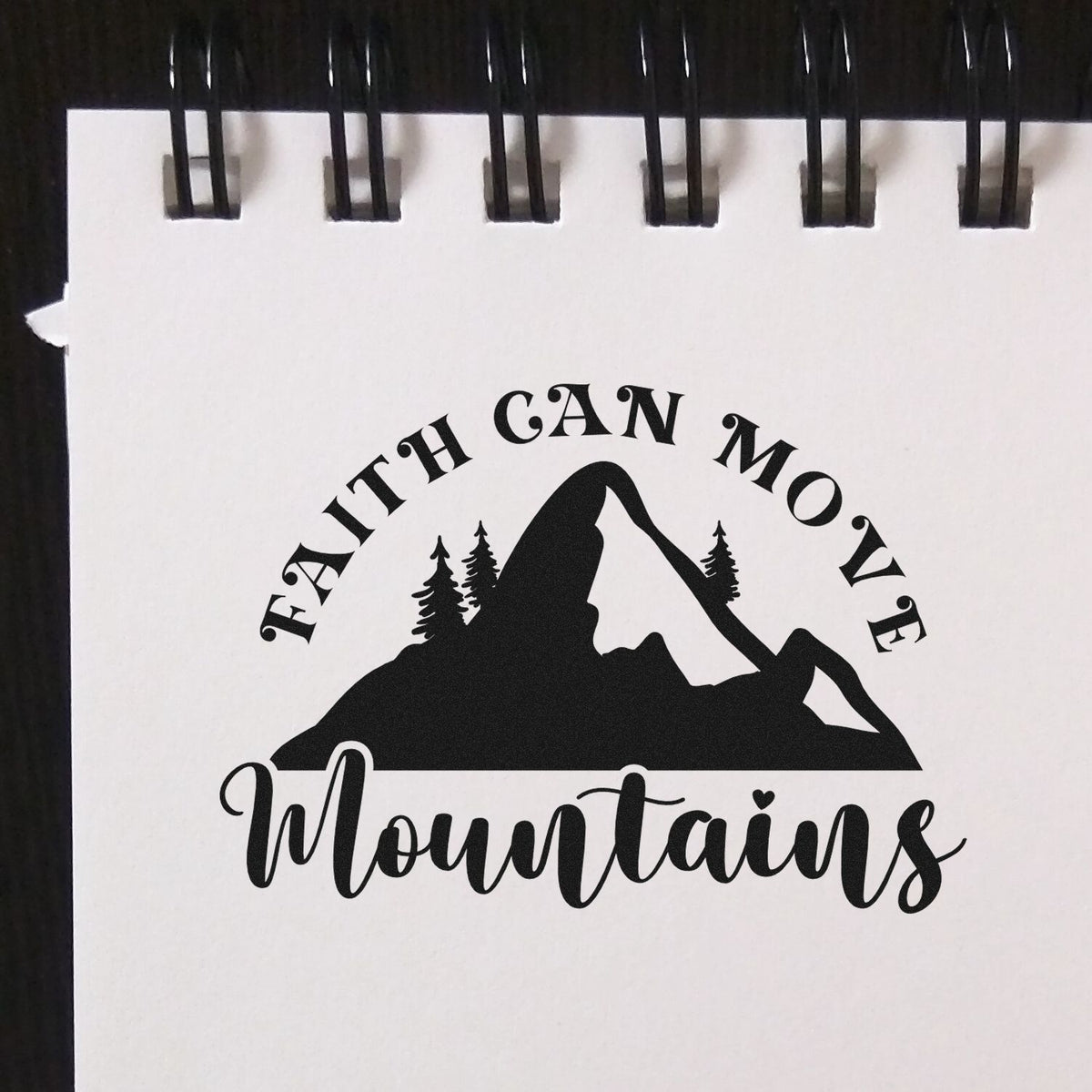 Black-and-white stamp seal reading Faith Can Move Mountains with mountain, pine trees, and cursive text.