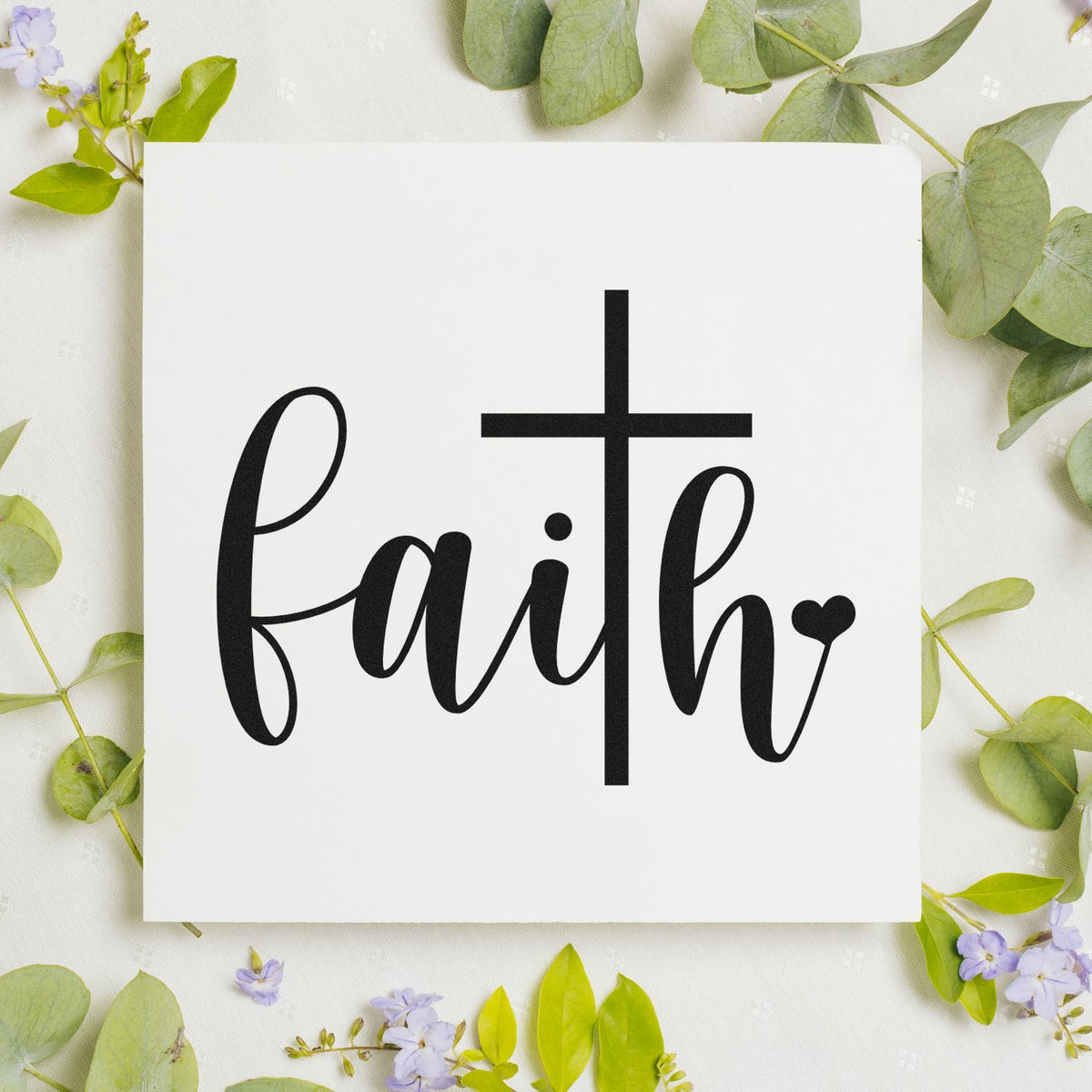 Black faith cross stamp on a white square seal, surrounded by green leaves and pale purple flowers.