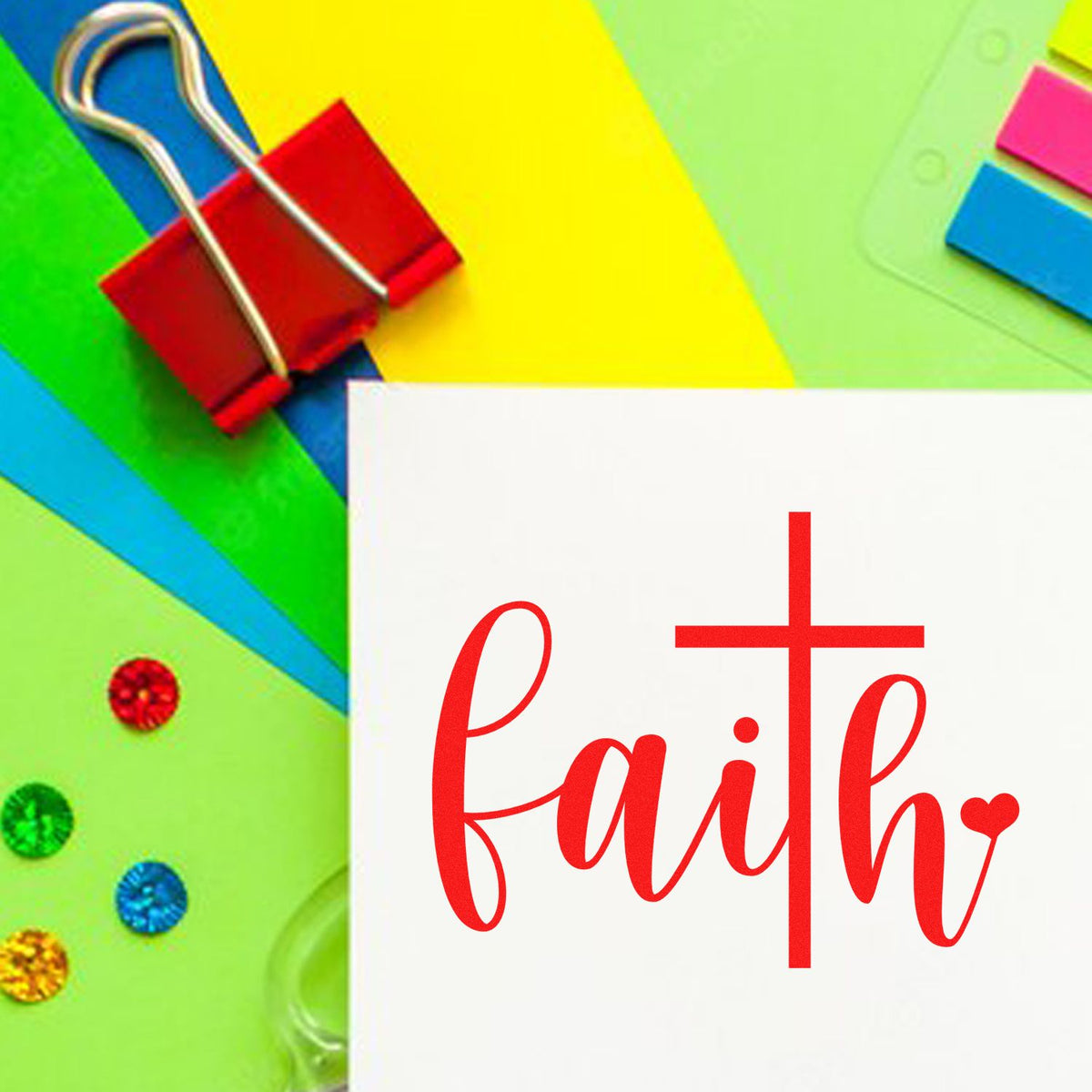 Red faith stamp and cross seal on white card, set among bright green, yellow, blue, and pink stationery.