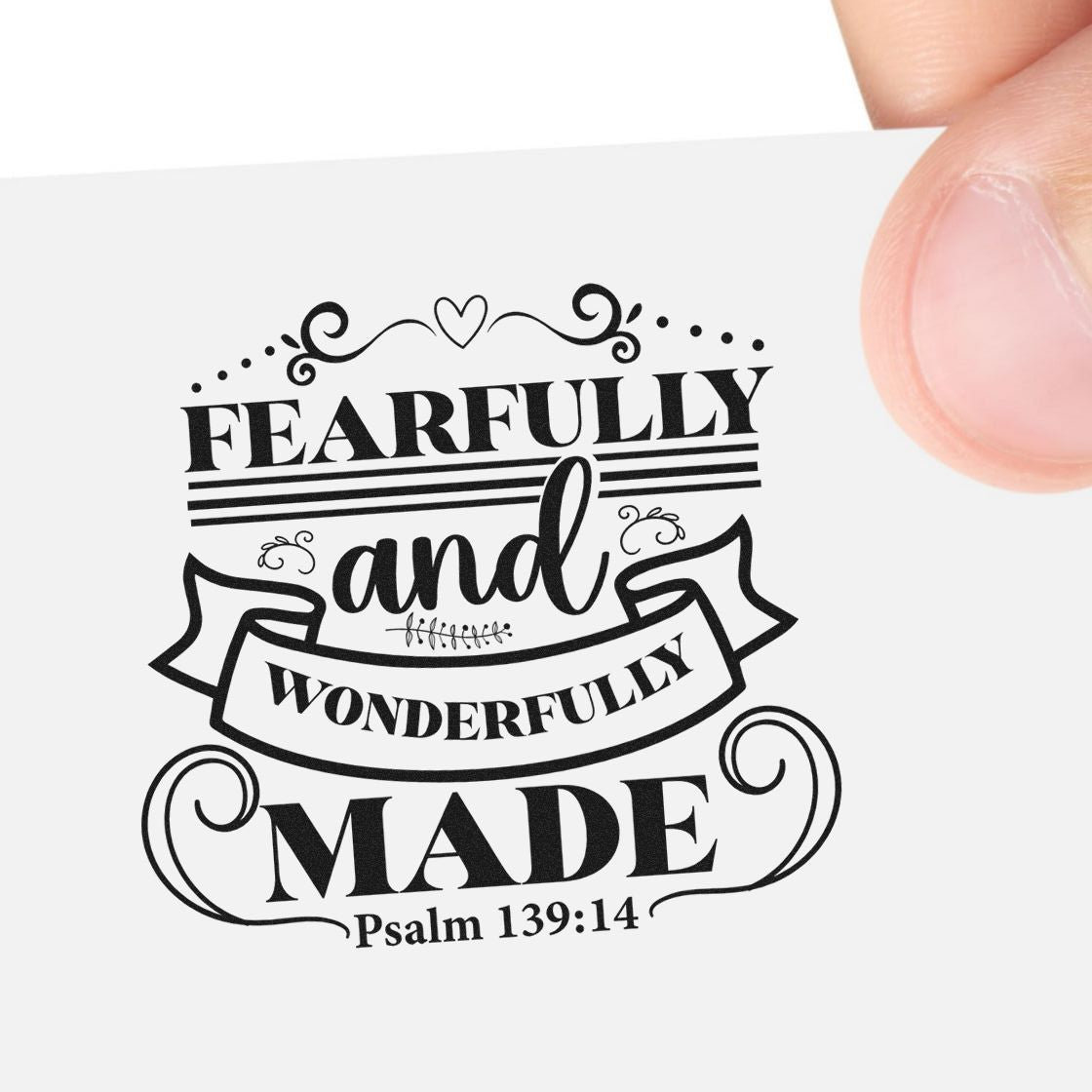 Black decorative stamp seal reading Fearfully and Wonderfully Made with Psalm 139:14 on white paper, held by fingers.