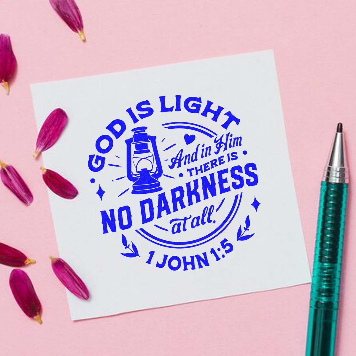 Blue Christian stamp seal product with lantern and verse on white card, pink background, purple petals, teal pen.