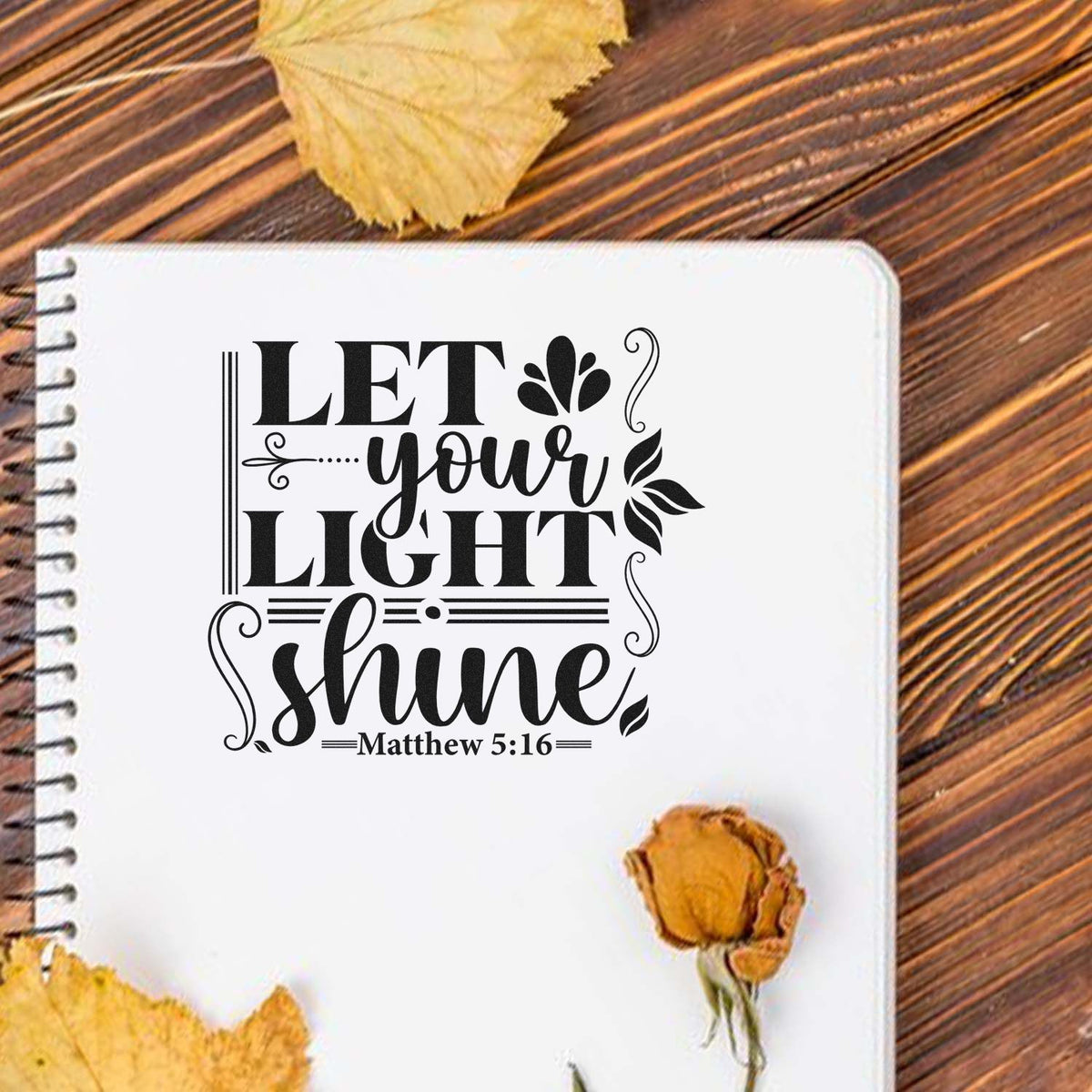 Custom stamp and seal design on a white notebook: black Let your light shine Matthew 5:16 with autumn leaves on wood.