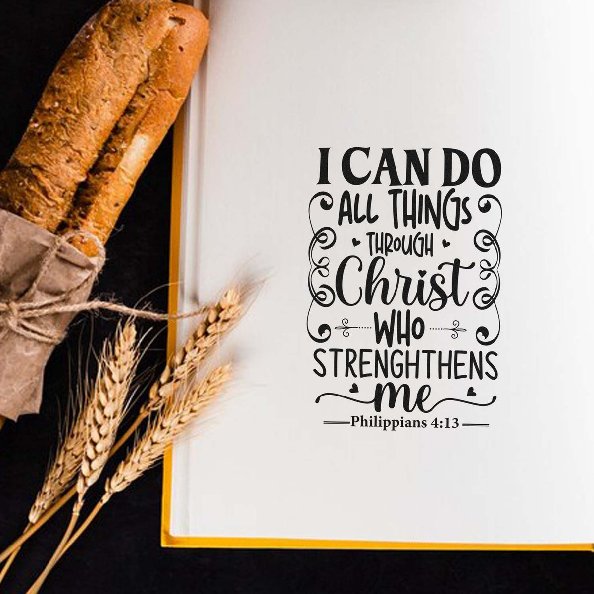 Black Christian quote stamp/seal on white background, beside rustic bread and wheat, with gold trim and Philippians 4:13.