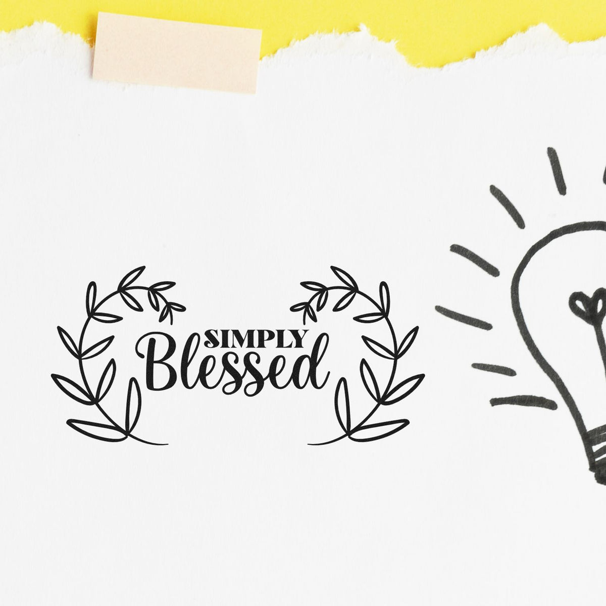 Black Simply Blessed stamp with leafy wreath on white paper, yellow torn tape, and partial lightbulb seal.