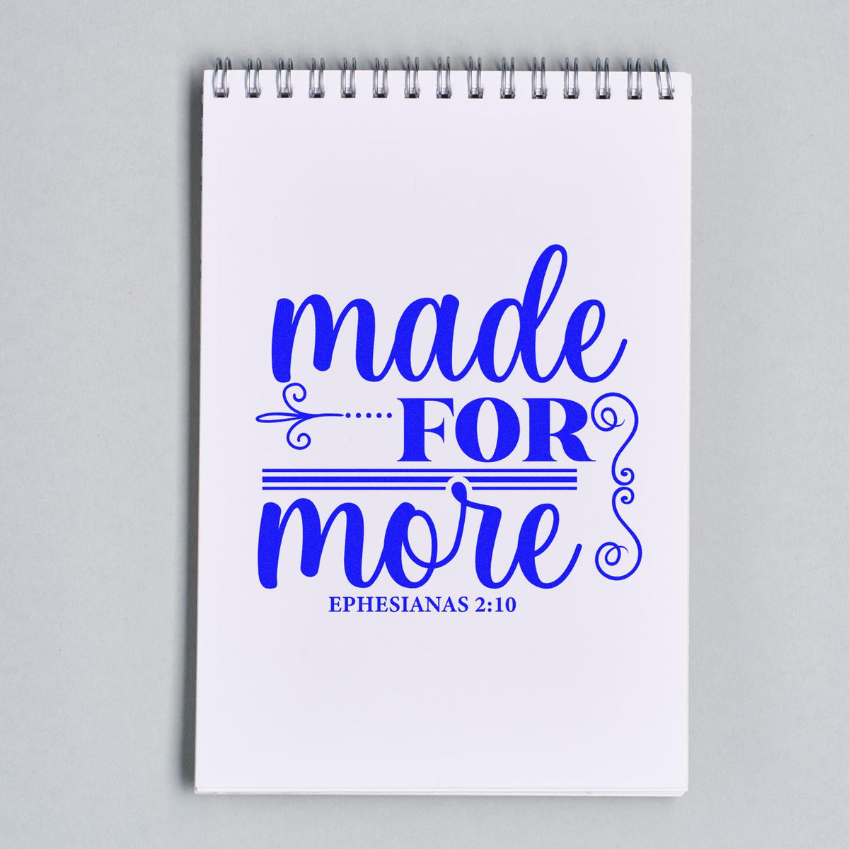 Blue stamp-and-seal design on white spiral notebook, reading made for more with Ephesians 2:10.