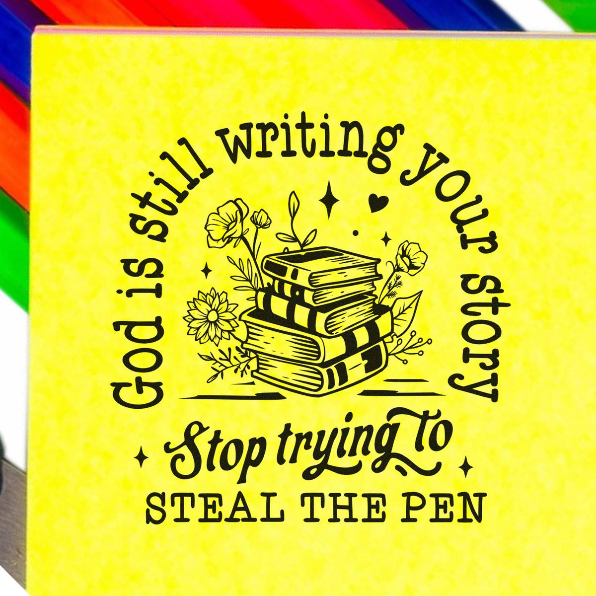 Yellow stamp seal with black stacked books and flowers, reading God is still writing your story, stop trying to seal the pen.