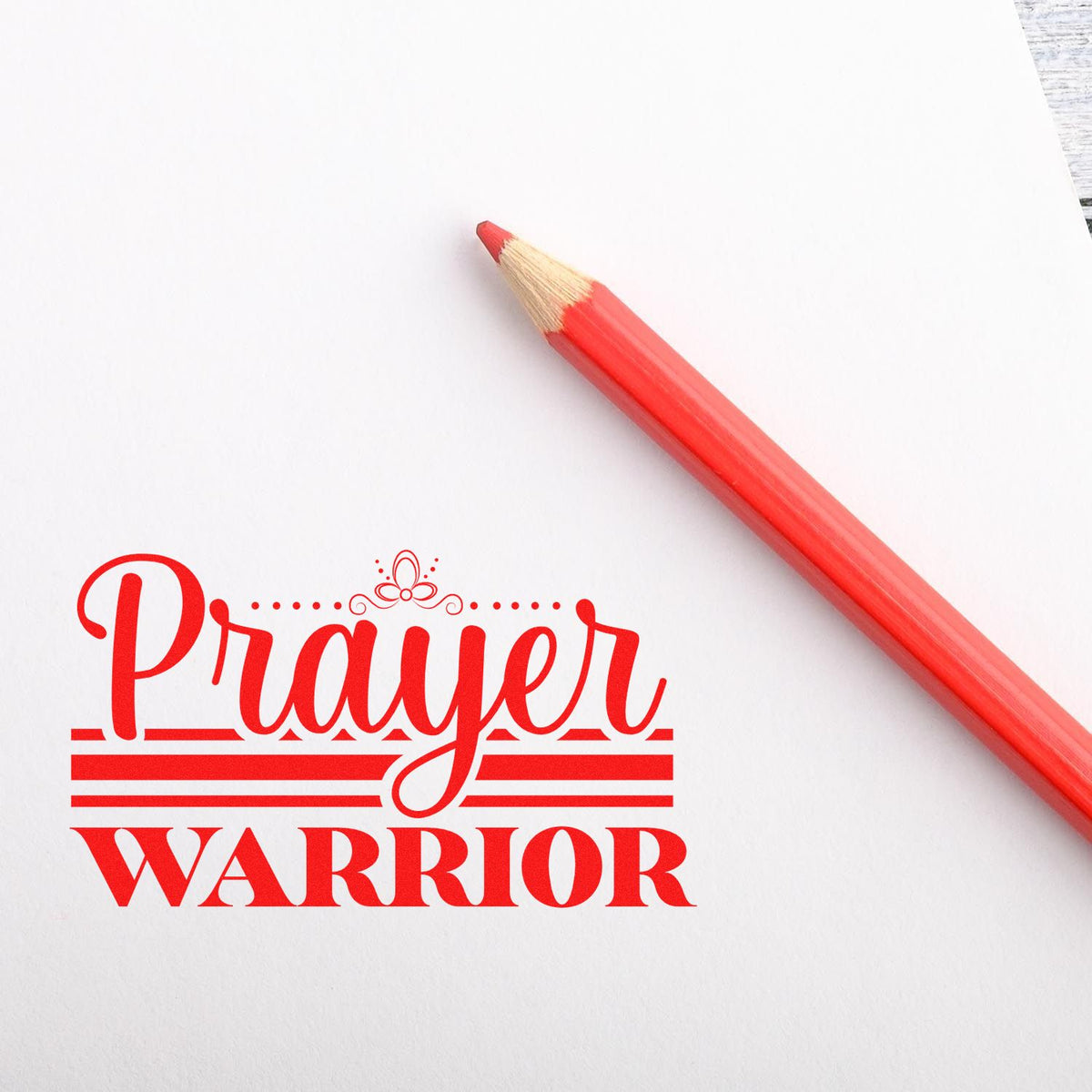 Red pencil beside a red Prayer Warrior stamp and seal design on white paper