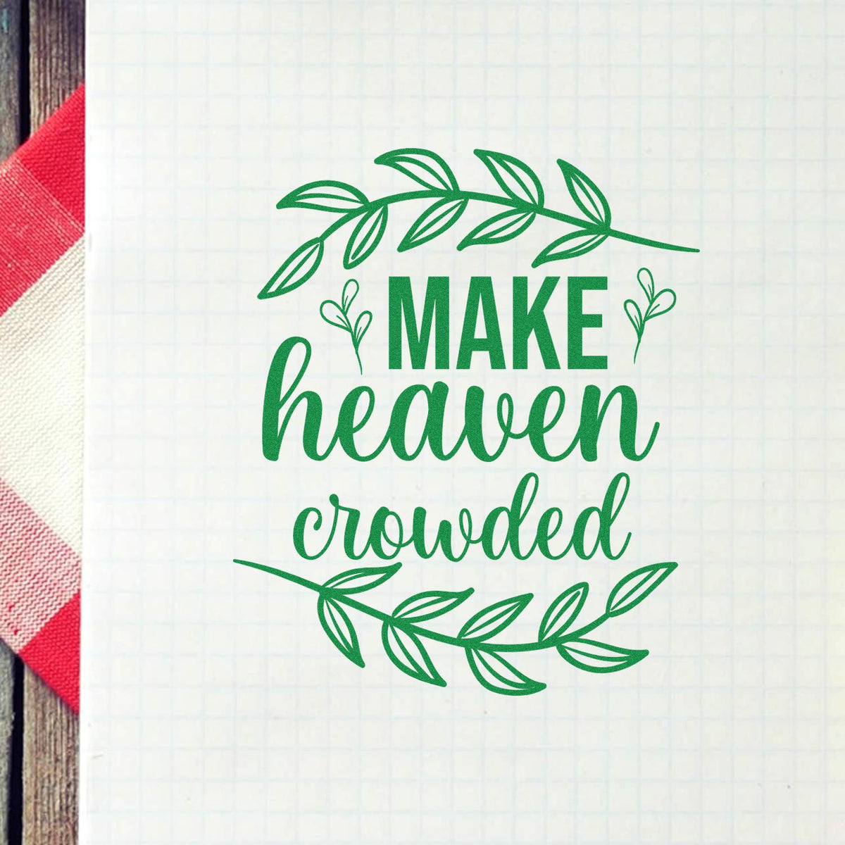 Green botanical stamp seal reading Make heaven crowded on white grid paper, framed by leafy branches.