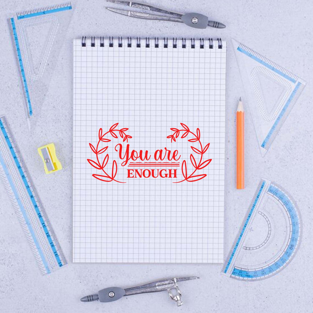 Red You are enough stamp-and-seal on graph notebook, with compass, pencil, and blue drafting rulers.