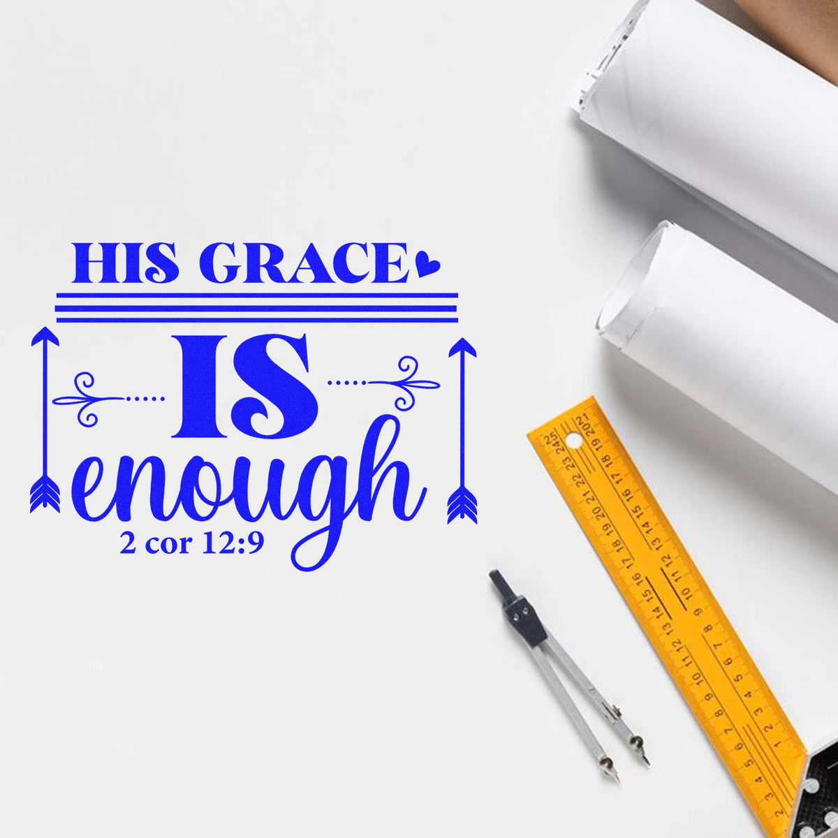 Blue custom stamp/seal reading His Grace is enough on white paper, with yellow ruler and drafting compass.