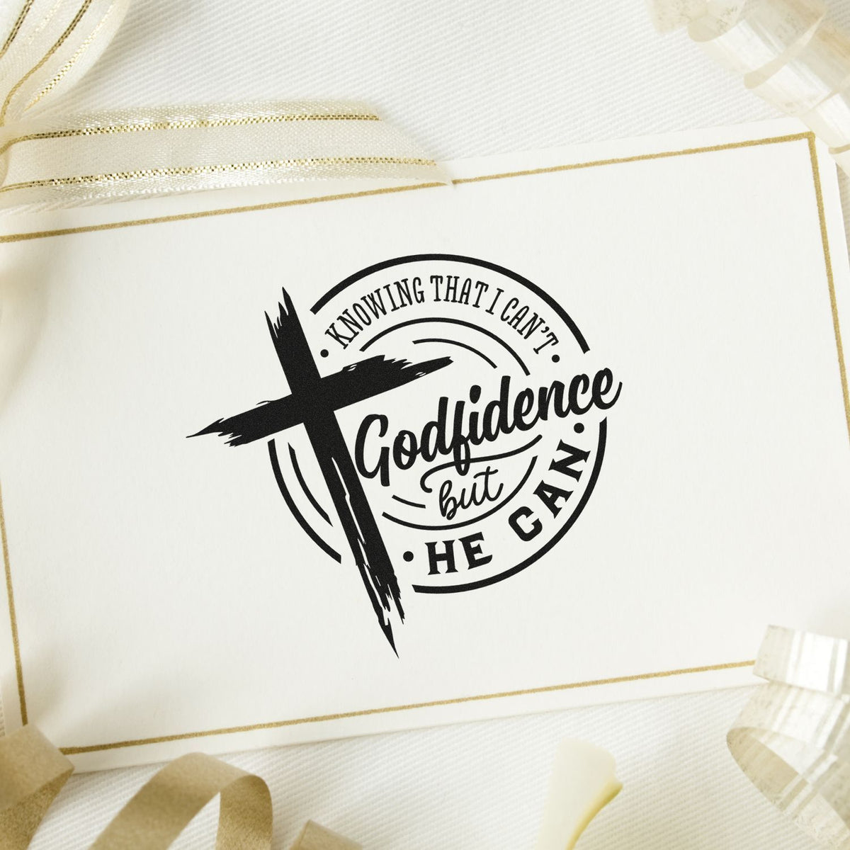 Black Christian stamp seal with cross and Godfidence but He can on cream card with gold trim and ribbon.