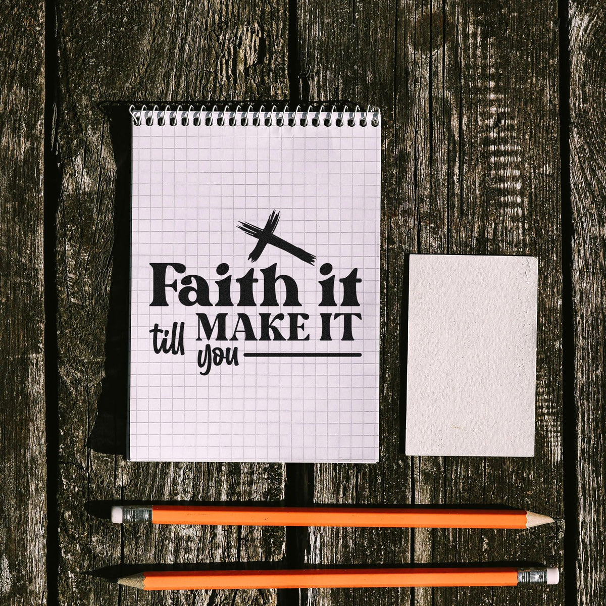 Faith it till MAKE IT stamp design on white graph notepad, plus blank seal card and orange pencils on dark wood.