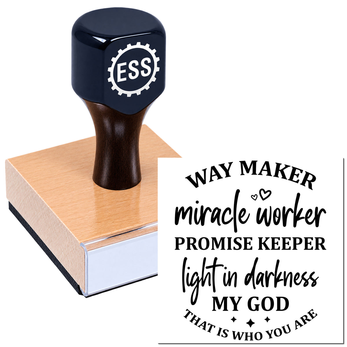Black-handled rubber stamp on a pink block with faith seal text: "Way Maker, Miracle Worker, Promise Keeper, Light in Darkness."