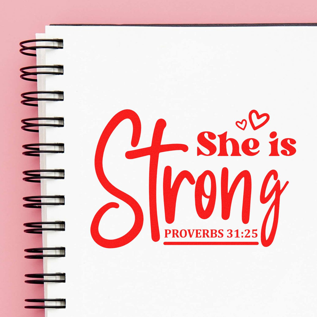 Red She is Strong Proverbs 31:25 stamp-and-seal design on white spiral notebook, with hearts and pink background.