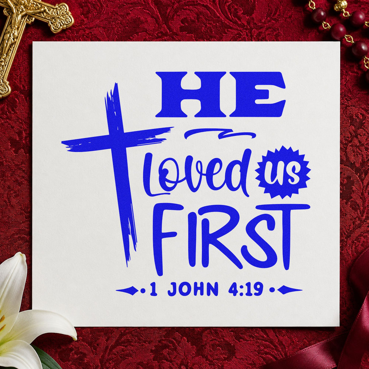 He Loved Us First craft stamp imprinted in blue ink on paper, a design suited to newborn gifts.
