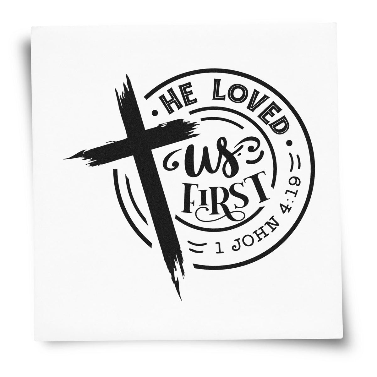 Black Christian stamp seal design with bold cross, He loved us first, and 1 John 4:19 on white.