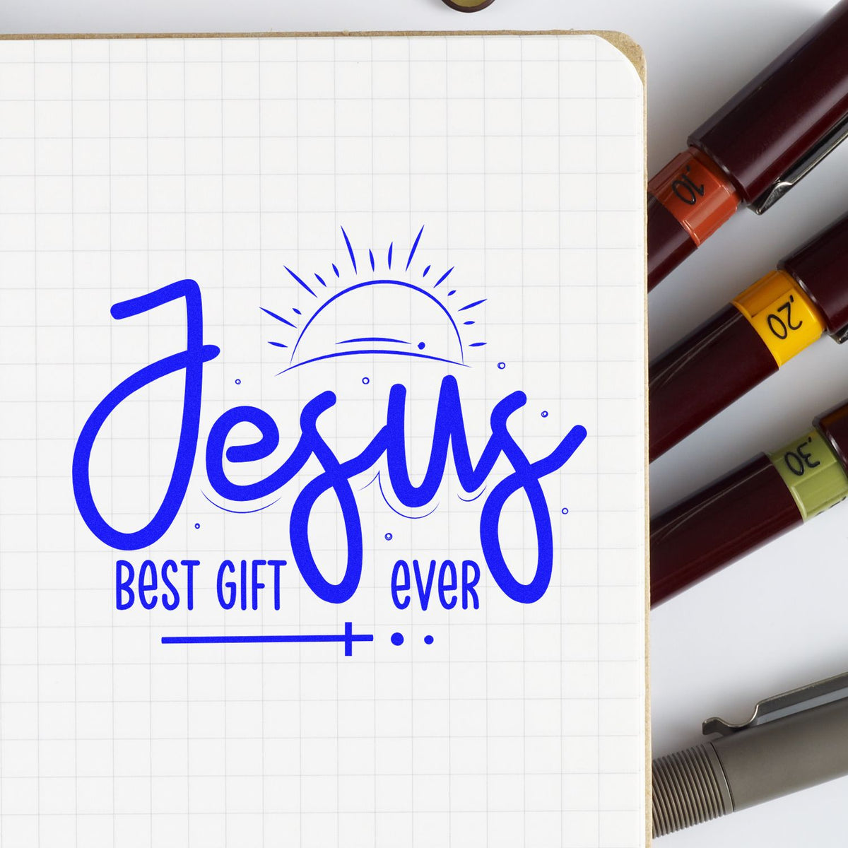 Blue Jesus Best Gift Ever stamp design on grid paper, with burgundy seal pens and colored number bands at right.