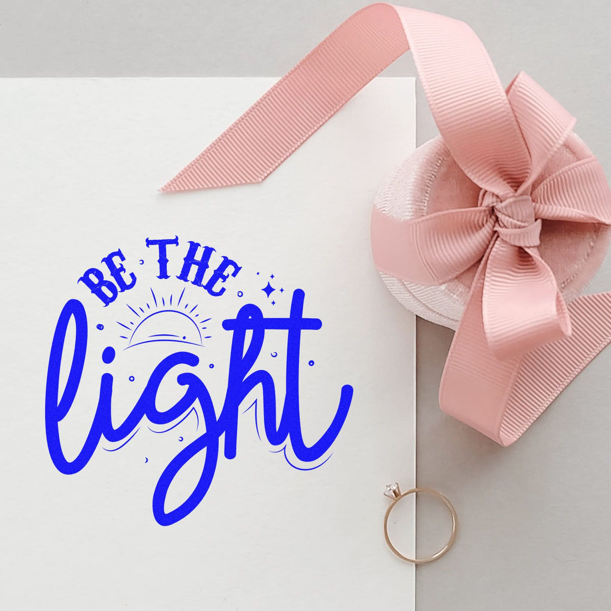 White card showing blue Be the light stamp, pink ribbon bow seal, and gold ring seal.