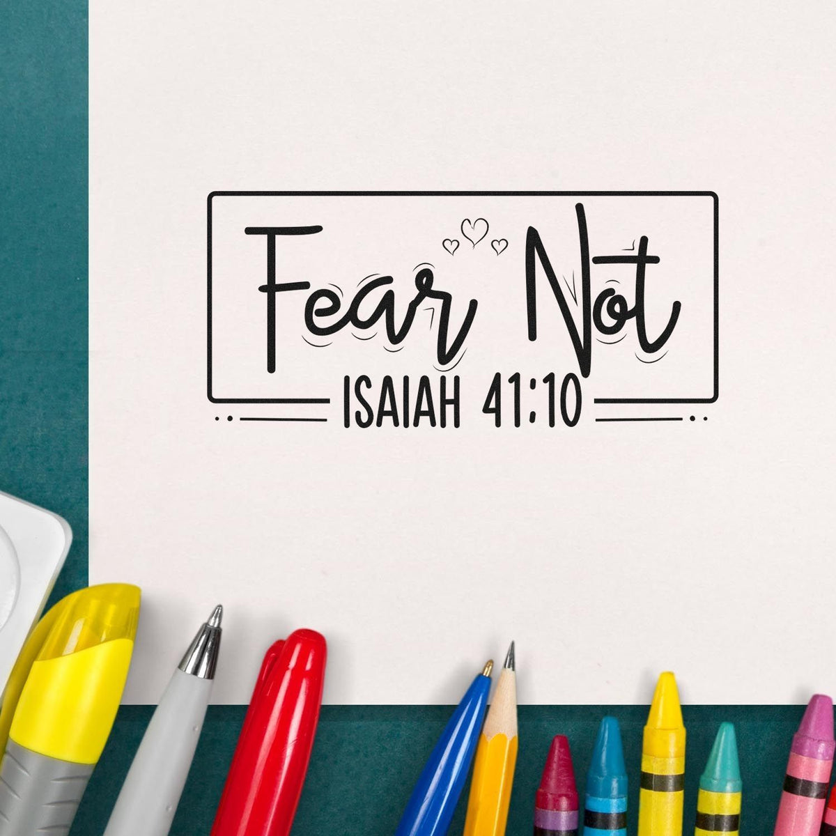 Black Fear Not Isaiah 41:10 stamp seal on white paper, surrounded by colorful markers and pens