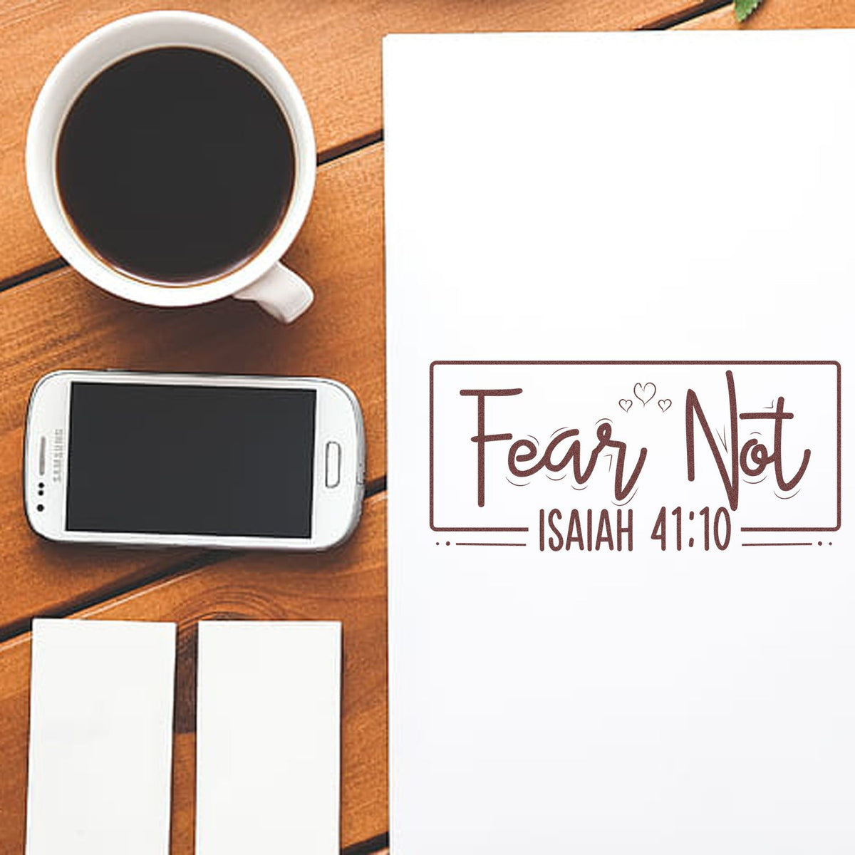Brown Fear Not Isaiah 41:10 stamp and seal design on white paper, beside coffee, smartphone, and blank labels.