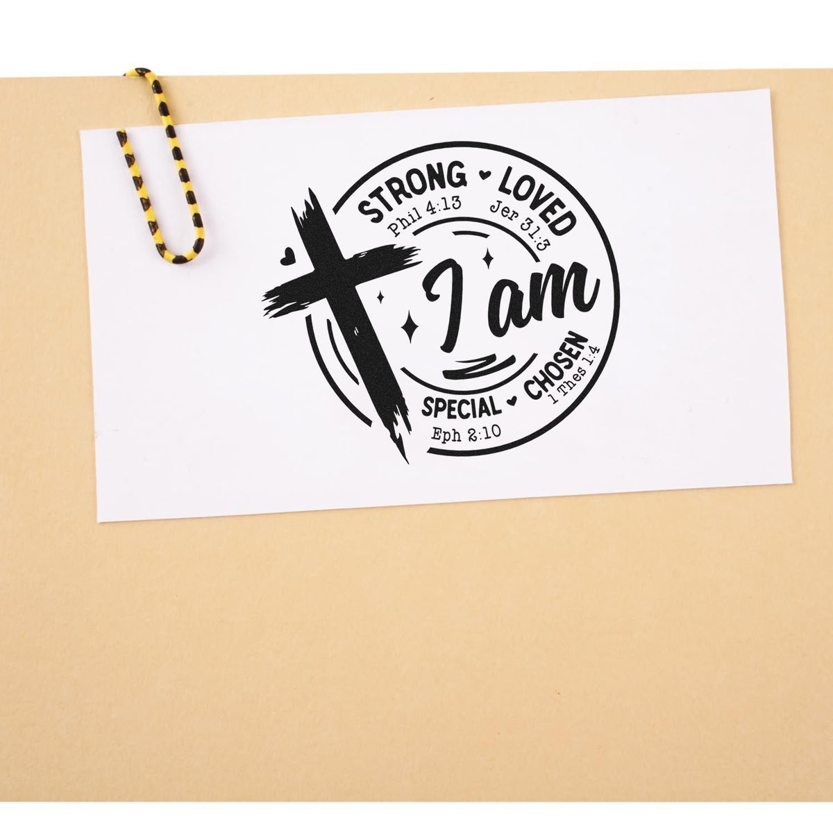 Black rubber stamp seal on white card with cross and I am strong, loved, chosen text on a beige background.