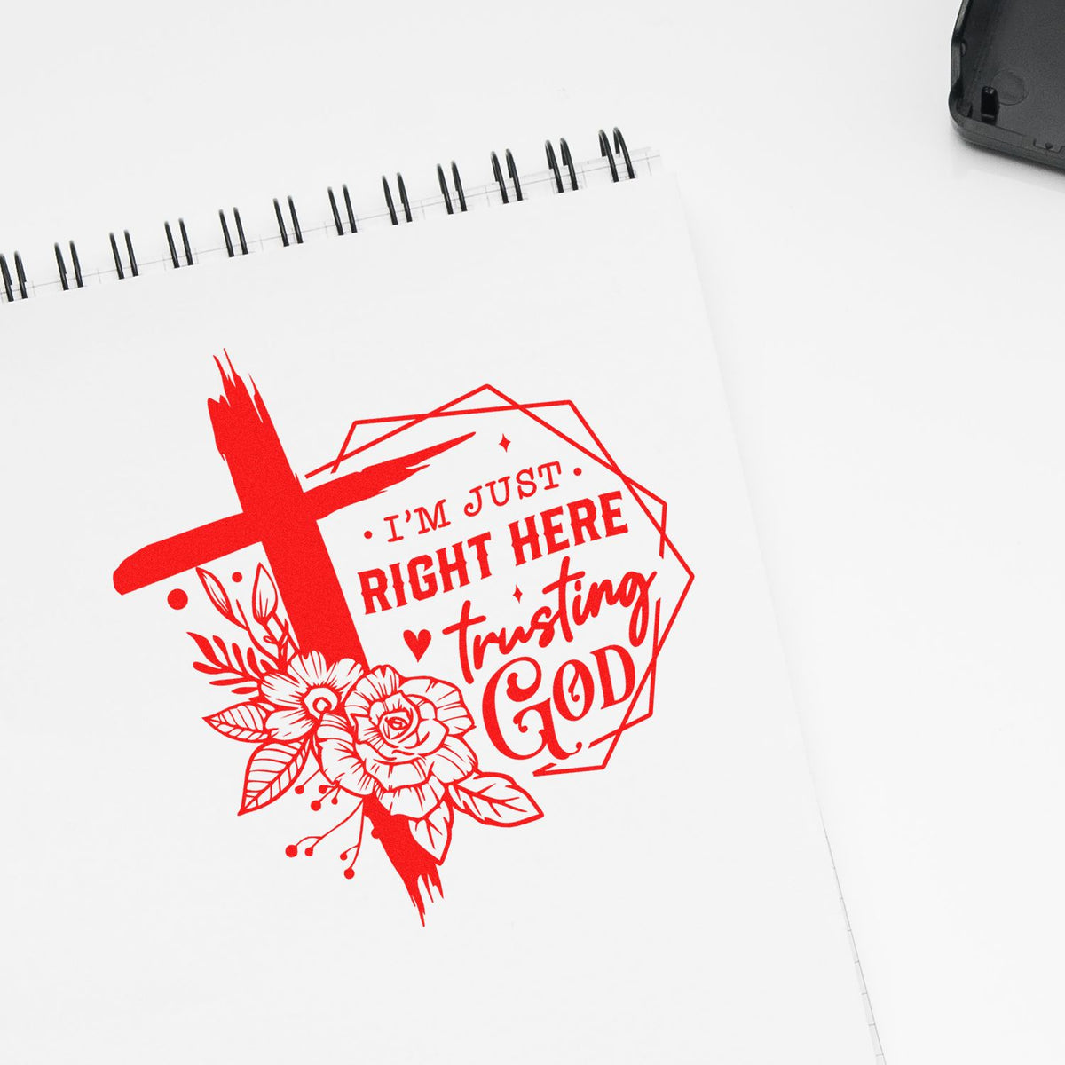 Red custom stamp seal on white spiral notebook, with floral cross and text Im just right here trusting God