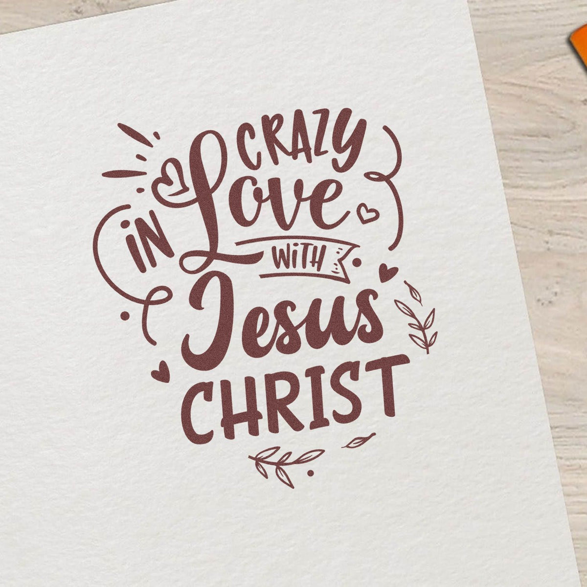 Maroon decorative stamp seal design reading Crazy in Love with Jesus Christ on white paper, with hearts and leaf accents.