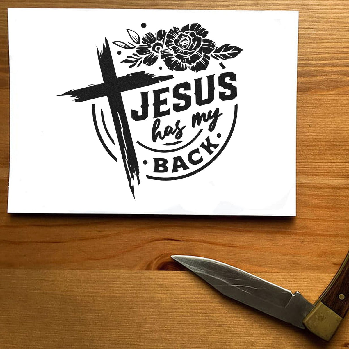 Black stamp seal design with cross, floral accents, and Jesus has my back on white paper.