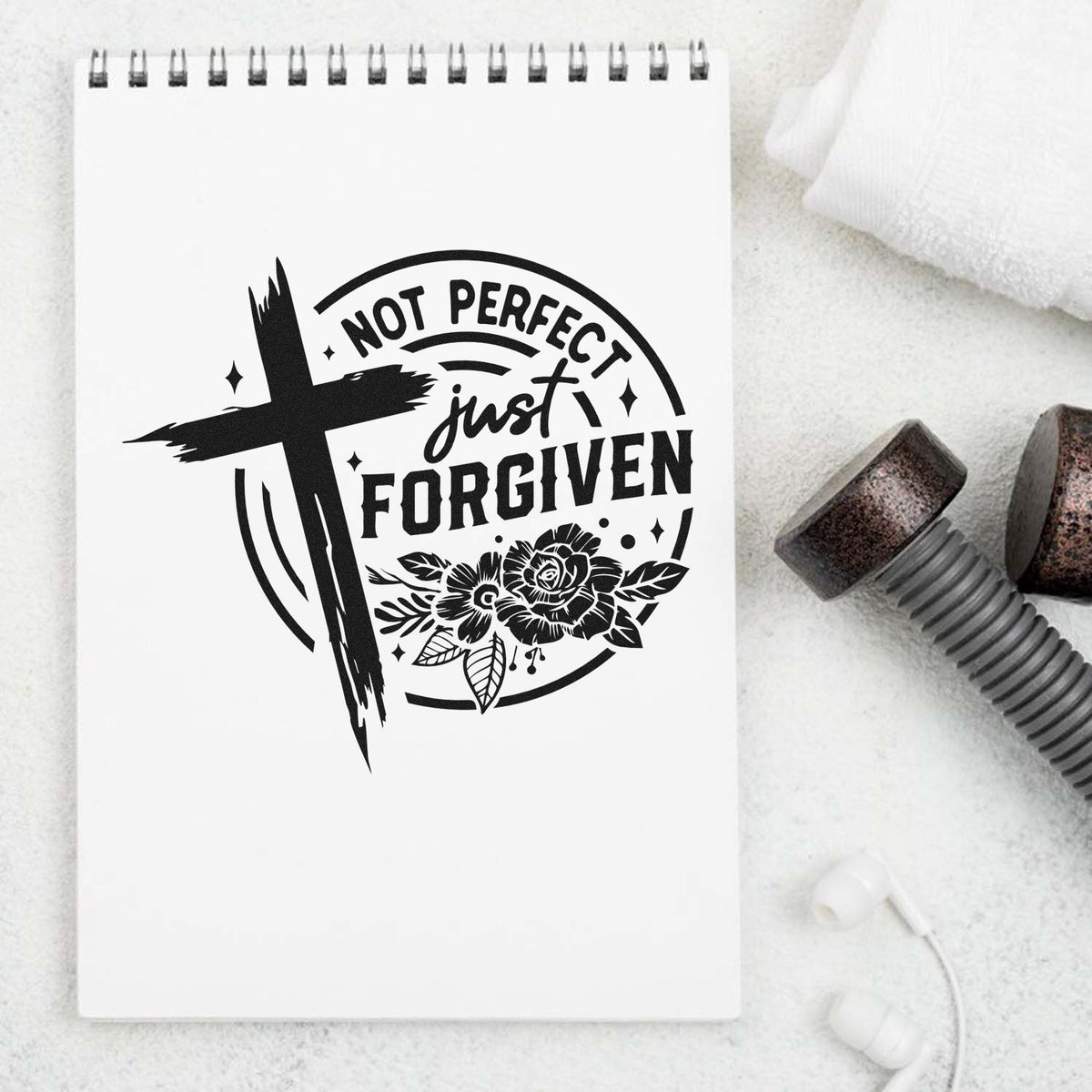 Black Not Perfect, Just Forgiven cross and floral stamp design on a white spiral notebook, with wax seal tools nearby.
